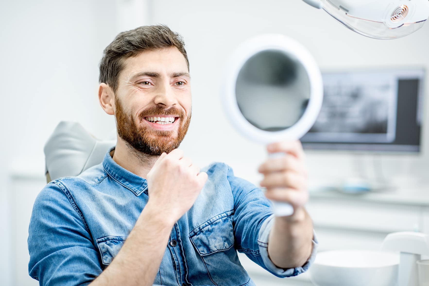 man looking in mirror during consultation with Cosmetic Dentist in Cumming, GA