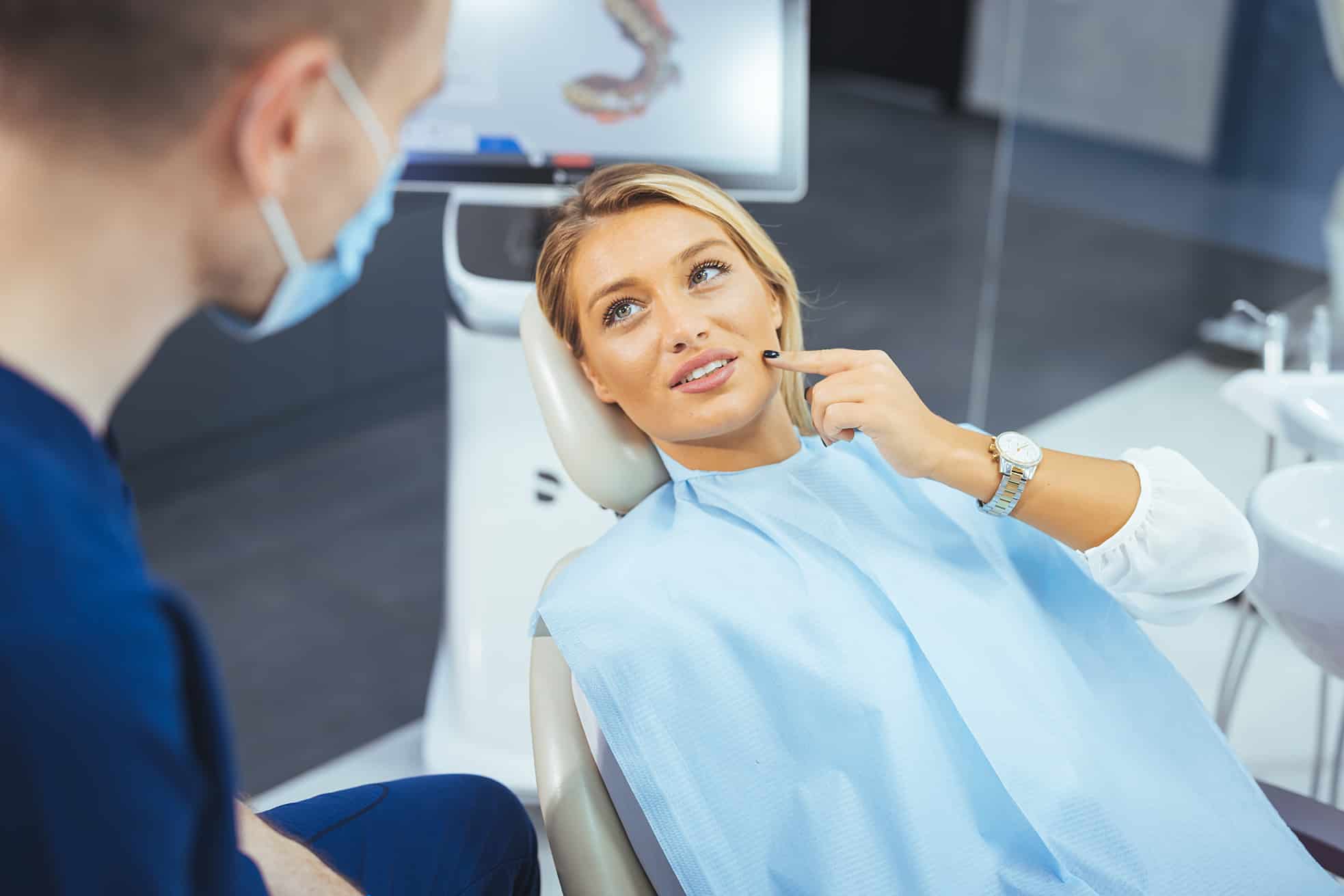 woman pointing to her jaw during a consultation at All Smiles Family & Cosmetic Dentistry in Cumming, GA