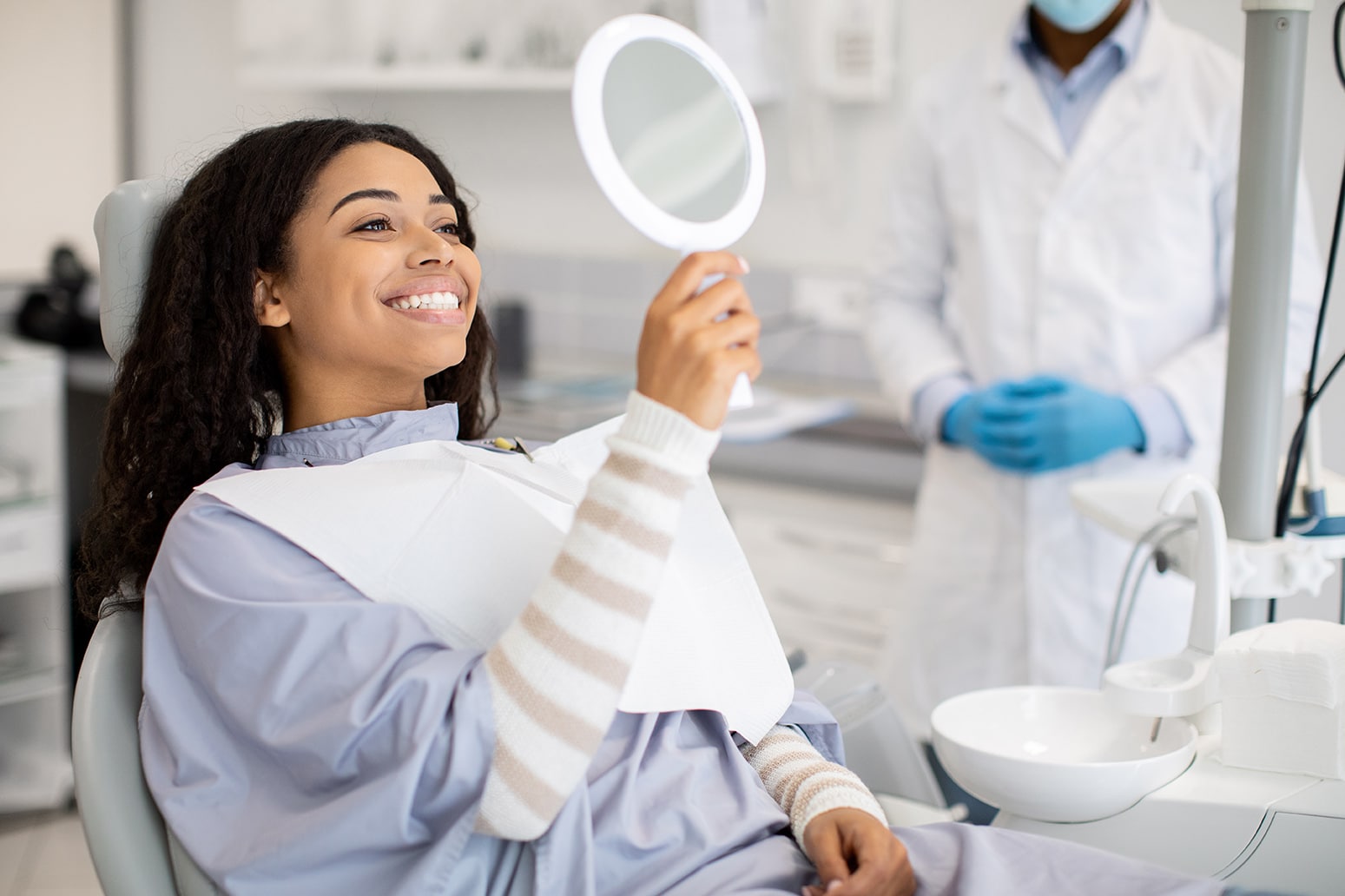 dental patient smiling in a mirror during a preventive dental appointment at all smiles family and cosmetic dentistry